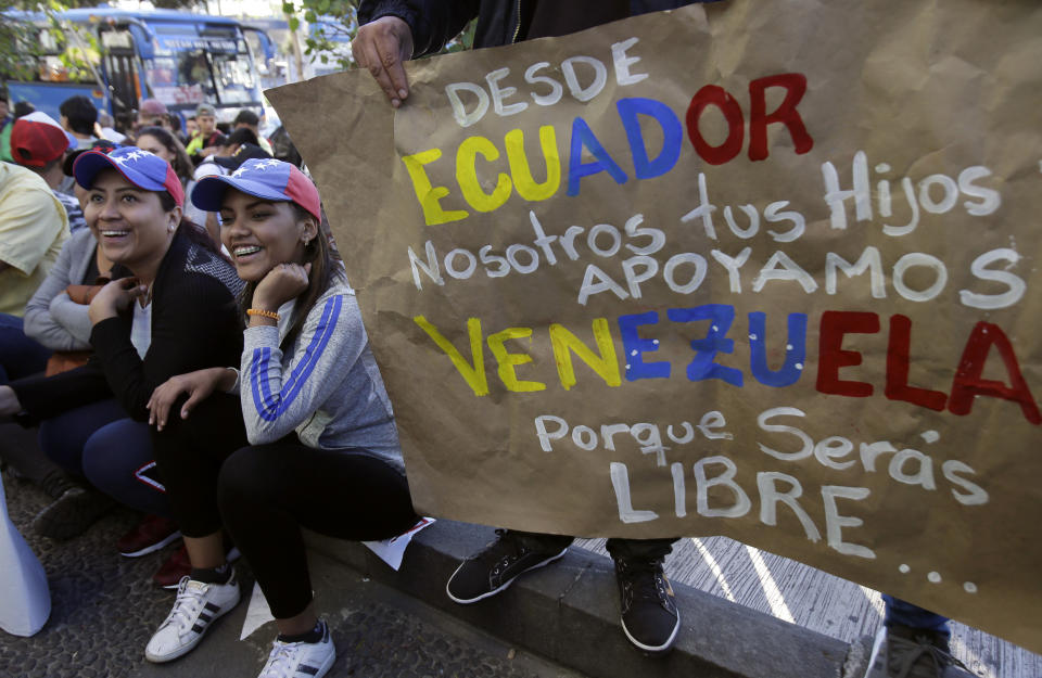 Venezuelan anti-government protesters gather outside their embassy with a sign that reads in Spanish "From Ecuador. We, your children, support Venezuela. Because you will be free..." in Quito, Ecuador, Wednesday, Jan. 23, 2019. Venezuelan migrants are rallying in favor of Juan Guaido, head of Venezuela's opposition-run congress, who today declared himself interim president of Venezuela. (AP Photo/Dolores Ochoa)