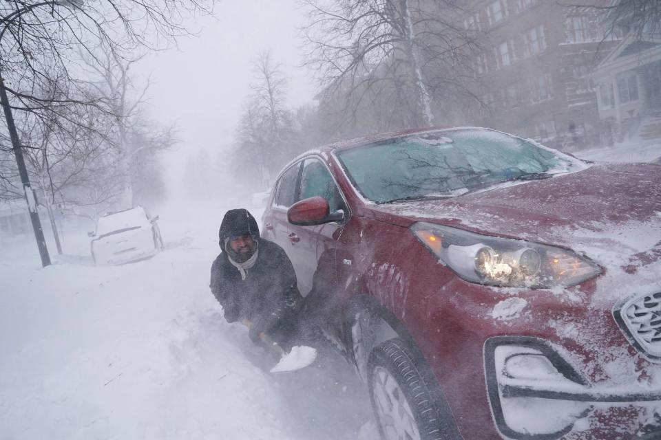 Gamaliel Vega tries to dig out his car on Lafayette Avenue after he got stuck in a snowdrift about a block from home while trying to help rescue his cousin (AP)