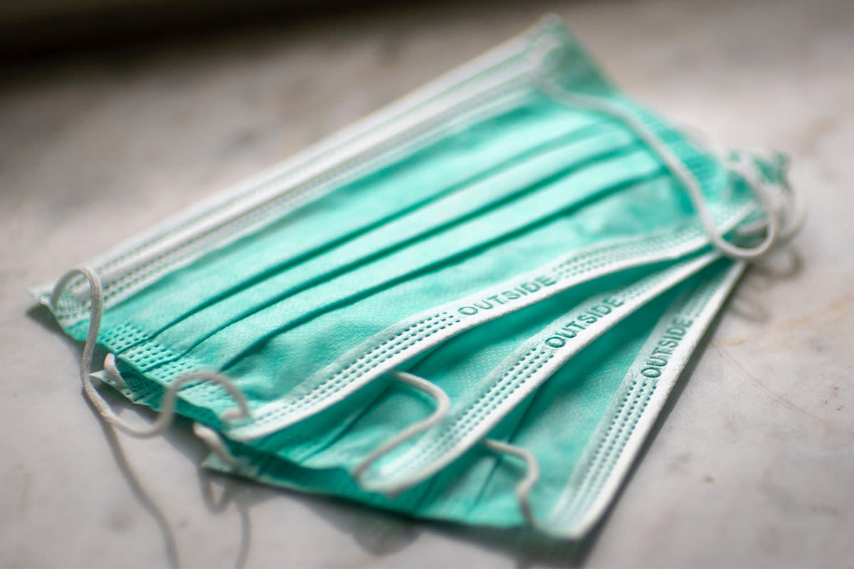 A pile of three single-use face masks on a counter