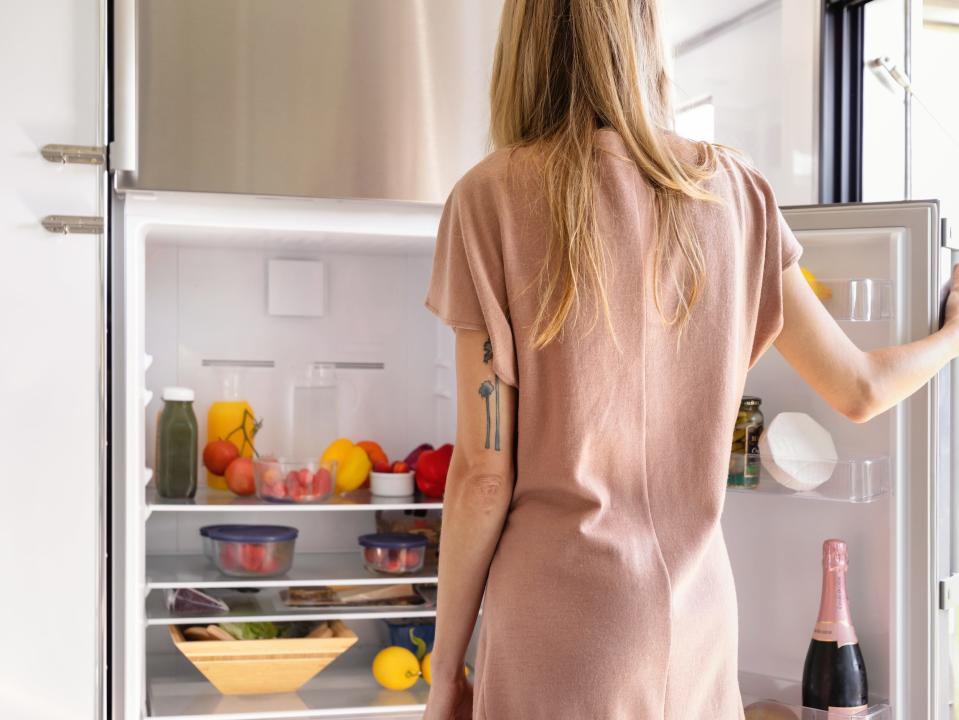 a person opening a full refrigerator