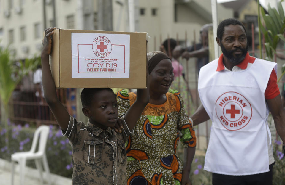 A child with his mother from Makoko Slum, carries their food parcel distributed by the Nigerian Red Cross, provided for those under coronavirus related movement restrictions, in Lagos, Nigeria, Saturday, April 25, 2020. (AP Photo/Sunday Alamba)