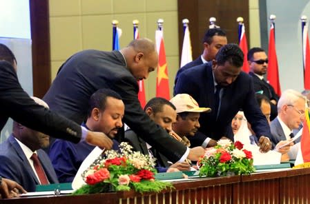 Deputy Head of Sudanese Transitional Military Council, Mohamed Hamdan Dagalo and Sudan's opposition alliance coalition's leader Ahmad al-Rabiah sign power sharing deal, as Ethiopia's Prime Minister Abiy Ahmed witnesses, in Khartoum