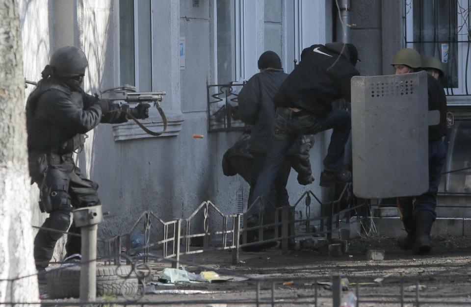 FILE - In this file photo taken on Feb. 18, 2014, a riot police officer shoots during clashes with protesters outside Ukraine's parliament in Kyiv, Ukraine. On Nov. 21, 2023, Ukraine marks the 10th anniversary of the uprising that eventually led to the ouster of the country’s Moscow-friendly president. (AP Photo/Efrem Lukatsky, file)