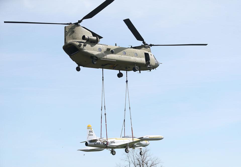An Army CH-47 Chinook helicopter carries the historic F-80 fighter jet from Sioux City to Camp Dodge for display at the camp Tuesday, April 11, 2023, in Johnston, Iowa.