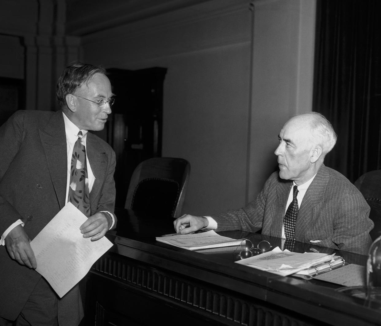 Waddill Catchings (left) of New York told the Securities Commission in Washington on June 2, 1937 that the Goldman Sachs trading corporation lost $289,566,330 of its $326,194,401 capital from 1928 to 1932. He asserted the loss was in line with the losses of other investors in the Wall Street crash of 1929. Catchings was head of the corporation. Commissioner Robert E. Healy of the Securities Exchange Commission is on the right. (AP Photo/Herbert K. White)