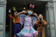 A visitor wearing a face mask take a selfie with the iconic cartoon characters Goofy and Pluto at the Hong Kong Disneyland, Friday, Sept. 25, 2020. Hong Kong Disneyland reopened its doors to visitors after closed temporarily due to the coronavirus outbreak. (AP Photo/Kin Cheung)