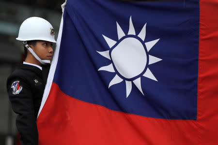 FILE PHOTO: A military honour guard holds a Taiwanese national flag as he attending flag-raising ceremony at Chiang Kai-shek Memorial Hall, in Taipei, Taiwan March 16, 2018. REUTERS/Tyrone Siu