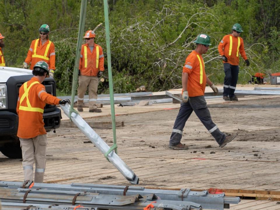 Hydro crews work around a transmission tower on the ground near Highway 417 and Hunt Club Road. (Jean Delisle/CBC - image credit)