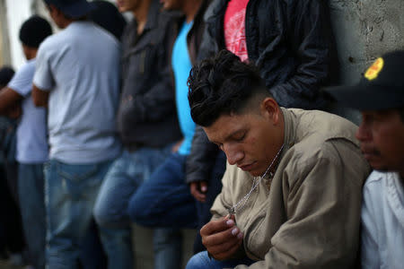 A Central America migrant caravan member holds a crucifix as he lines up to receive breakfast at the end of his journey through Mexico, prior to preparations for an asylum request in the U.S., at a shelter in Tijuana, Baja California state, Mexico April 27, 2018. REUTERS/Edgard Garrido