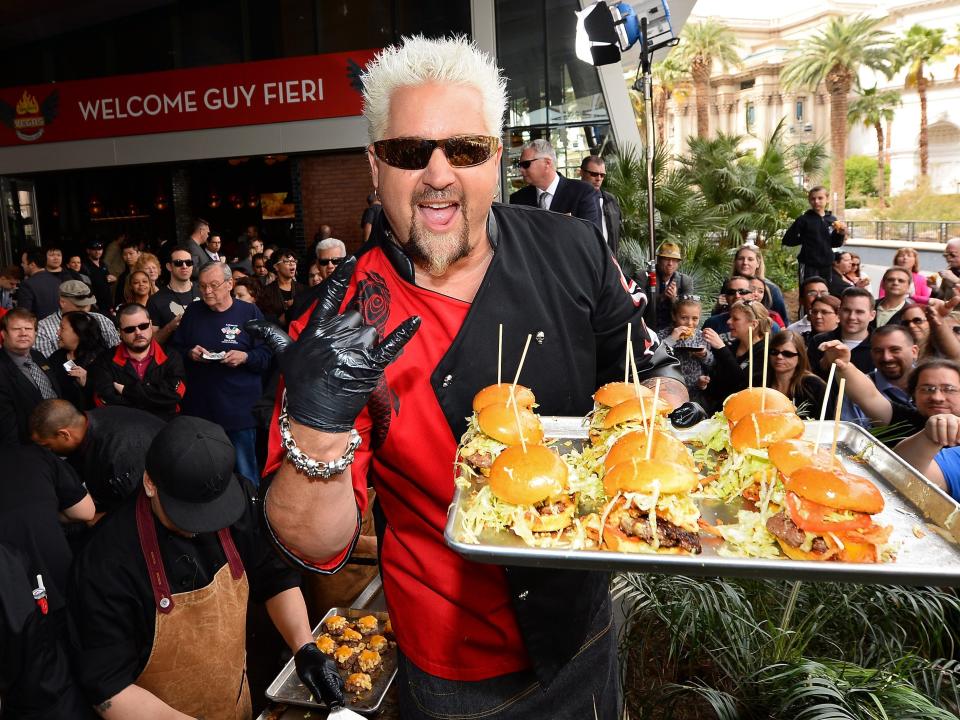 guy fieri holding hamburgers on a tray