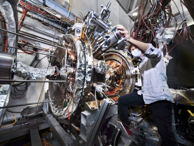 A person examining a piece of equipment at CERN's antimatter factory.