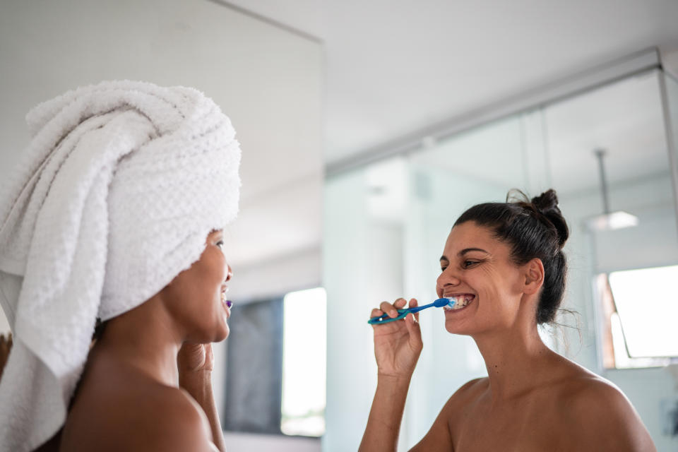 Female couple brushing teeth. (Getty Images)