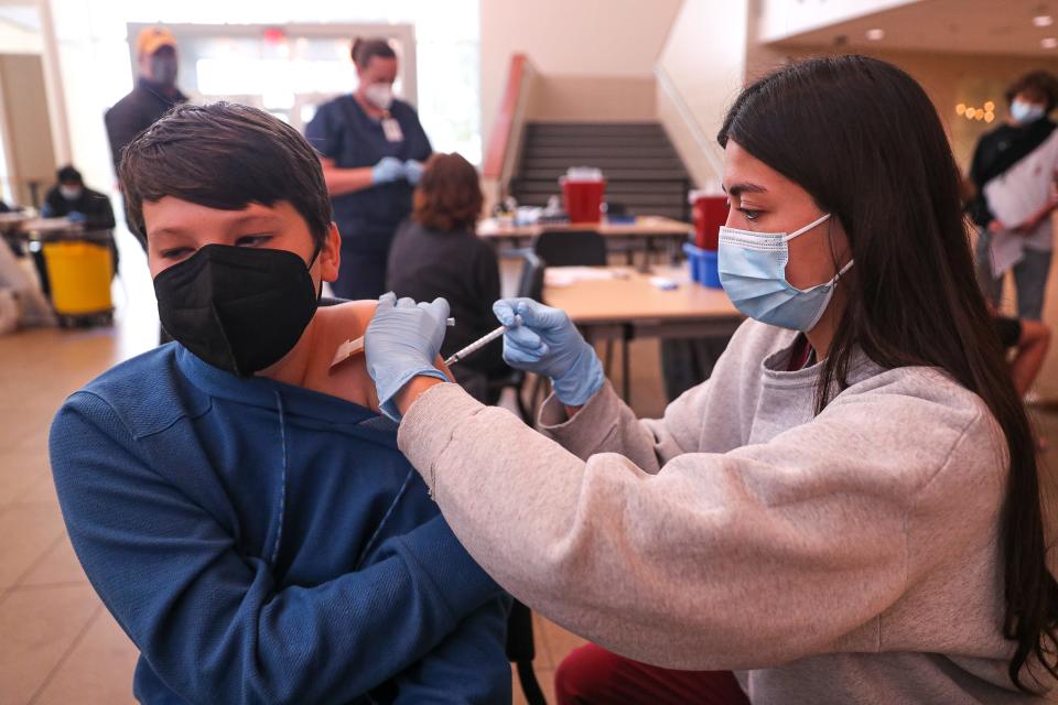 Vaccine administrator Isabella Grace, right, injects a dose of the Pfizer COVID-19 vaccine into the arm of Dashiell Custard (12), left, at a vaccine clinic for AISD families. Dell Children's Medical Center and Ascension Seton hosted a free COVID-19 vaccine event for Austin independent School District families on Jan. 8, 2022 at the AISD Performing Arts Center in Austin, Texas.