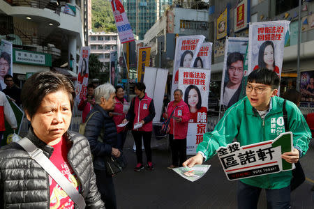 A supporter for pro-democracy candidate Au Nok-hin campaigns in front of a group of supporters for pro-government candidate Judy Chan during a Legislative Council by-election in Hong Kong, China March 11, 2018. REUTERS/Bobby Yip