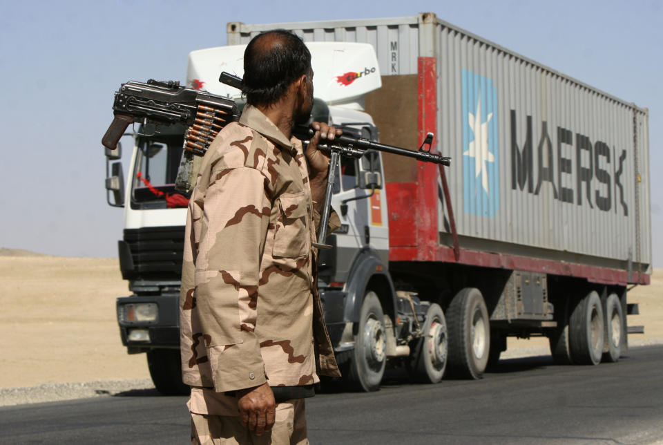 FILE - In this Oct. 27, 2010, file photo a private security contractor watches a NATO supply truck drive past in the province of Ghazni, south-west of Kabul, Afghanistan. Military contractors got up to half of the $14 trillion spent by the Pentagon since 9/11, a study by Brown University’s Costs of War project and the Center for International Policy said Monday, Sept. 13, 2021. (AP Photo/Rahmatullah Naikzad, File)