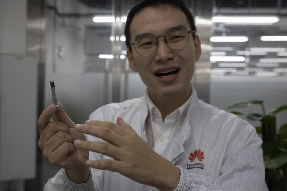 In this Aug. 21, 2019, photo, a Huawei research engineer holds up a coated screw designed to reduce signal interference at the Huawei Materials lab in Dongguan in Southern China's Guangdong province. Facing a ban on access to U.S. technology, Chinese telecom equipment maker Huawei is showing it increasingly can do without American components and compete with Western industry leaders in pioneering research. (AP Photo/Ng Han Guan)