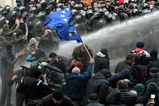 Riot police fire water cannons to break up a crowd of protesters outside the parliament building in Tbilisi