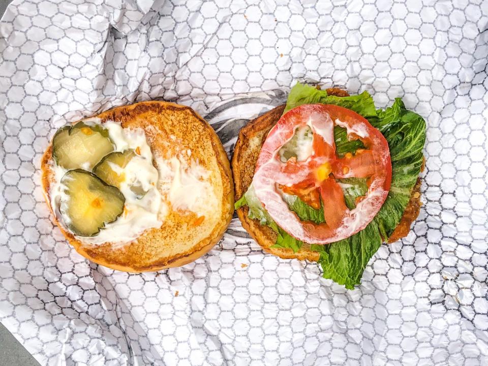 On the left, a bun from Wendy's fried-chicken sandwich with three small pickle slices and mayo. On the right, a bun with tomato and lettuce.