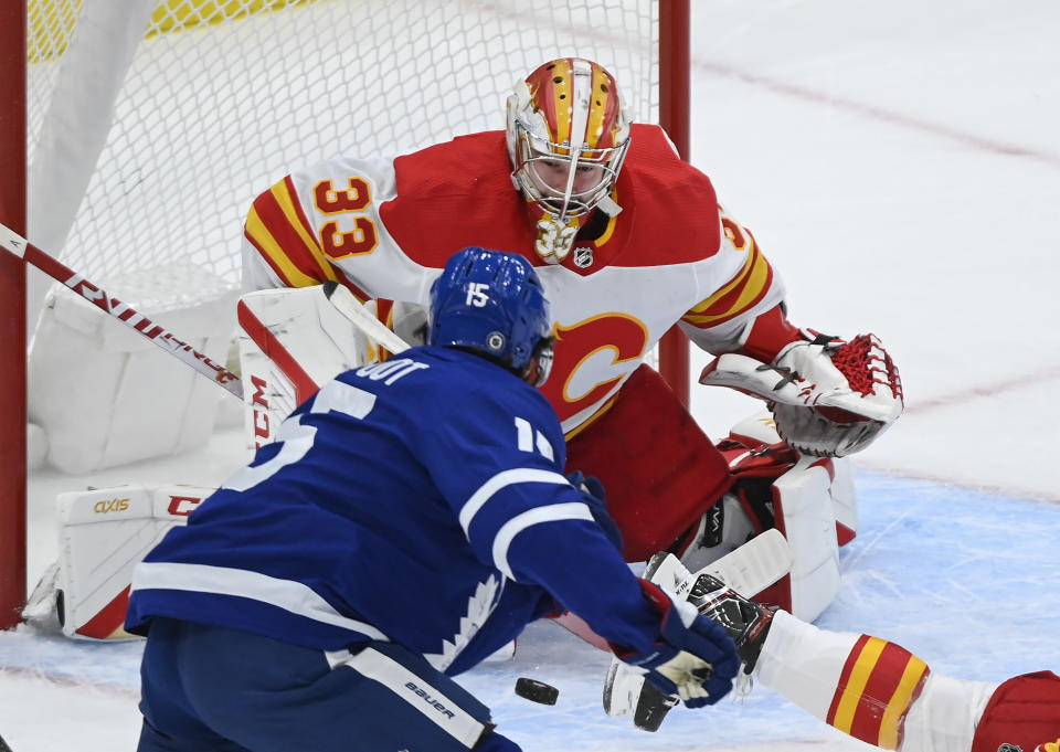 Calgary Flames goaltender David Rittich (33) makes a save against Toronto Maple Leafs forward Alexander Kerfoot (15) during first-period NHL hockey game action in Toronto, Saturday, March 20, 2021. (Nathan Denette/The Canadian Press via AP)