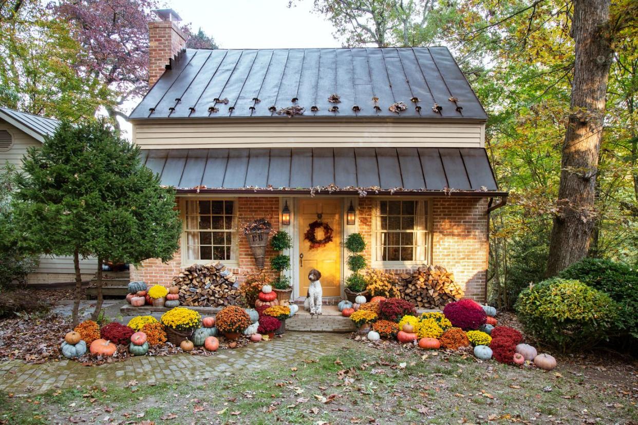 tin roofed brick cottage with pumpkins surrounding the walkway