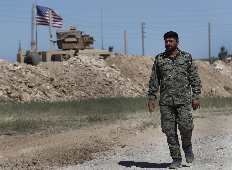 FILE - In this April 4, 2018 file photo, a U.S-backed Syrian Manbij Military Council soldier passes a U.S. position near the tense front line with Turkish-backed fighters, in Manbij, north Syria. U.S. President Donald Trump's decision Wednesday Dec. 19, 2018, to withdraw U.S. troops from Syria has rattled Washington's Kurdish allies, who are its most reliable partner in Syria and among the most effective ground forces battling the Islamic State group. (AP Photo/Hussein Malla, File)