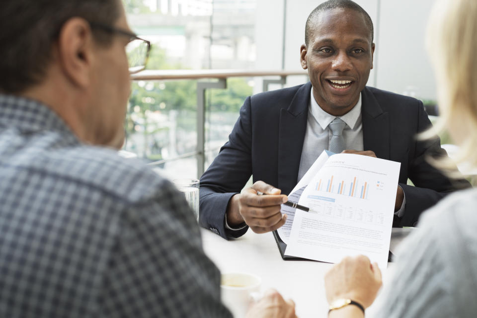 A mature couple sitting across from a financial advisor, reviewing a printed chart