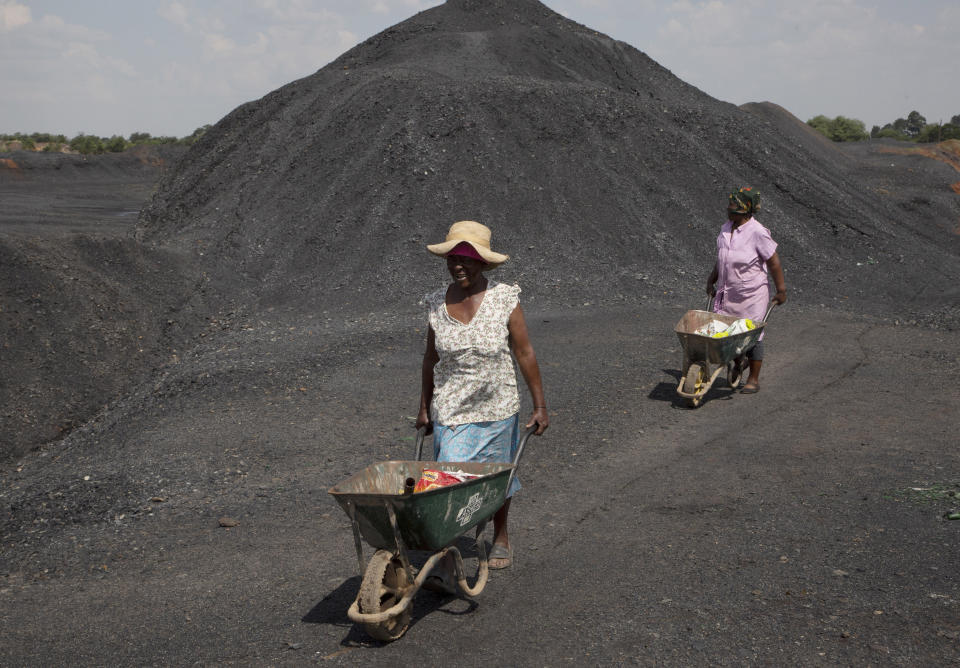 Women from the Masakhane Township, push wheelbarrows atop a coal mine dump at the coal-powered Duvha power station, near Emalahleni (formerly Witbank) east of Johannesburg, Thursday, Nov. 17, 2022. Living in the shadow of one of South Africa’s largest coal-fired power stations, residents of Masakhane fear job losses if the facility is closed as the country moves to cleaner energy. A significant polluter because it relies on coal to generate about 80% of its electricity, South Africa plans to reduce that to 59% by 2030 by phasing out some of its 15 coal-fired power stations and increasing its use of renewable energy. (AP Photo/Denis Farrell)