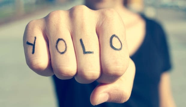 closeup of a young man with the word yolo, for you only live once, tattooed in his hand, with a filter effect