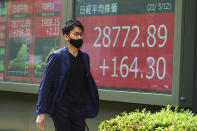 A man wearing a protective mask walks in front of an electronic stock board showing Japan's Nikkei 225 index at a securities firm Wednesday, May 12, 2021, in Tokyo. Asian stock markets retreated Wednesday as investors looked ahead to U.S. data they worry will show inflation is picking up.(AP Photo/Eugene Hoshiko)