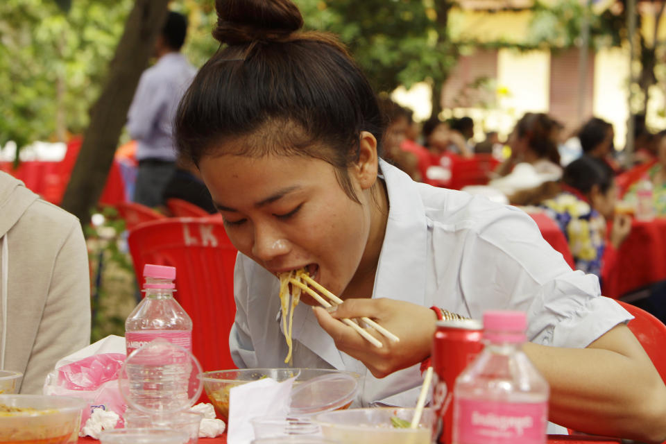 A Cambodian garment worker eats noodle at a Buddhist pagoda outside Phnom Penh, Cambodia, Sunday, June 9, 2019. The bitter decadeslong rivalry between Hun Sen, Cambodia's strongman leader, and Sam Rainsy, the self-exiled chief political rival and critic, has sometimes played out in deadly violence. But on Sunday, soup rather than blood was likely to be spilled. (AP Photo/Heng Sinith)