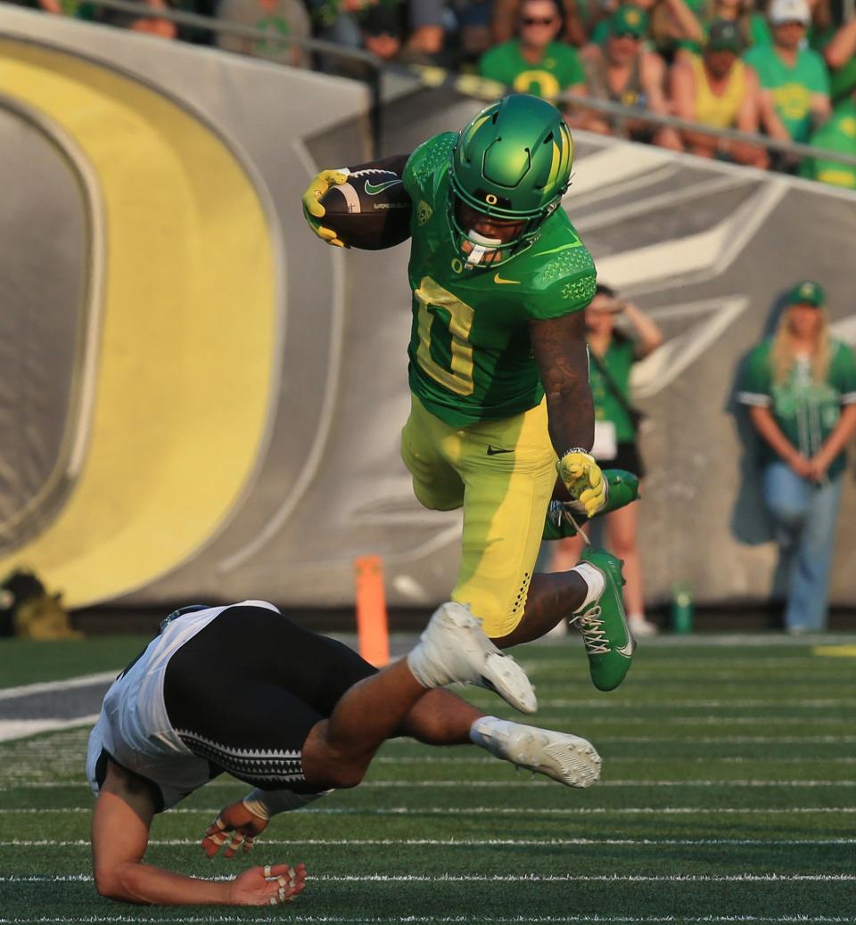 Oregon's Bucky Irving jumps over a Hawaii player during the first half in Eugene, Ore. Sept. 16, 2023.