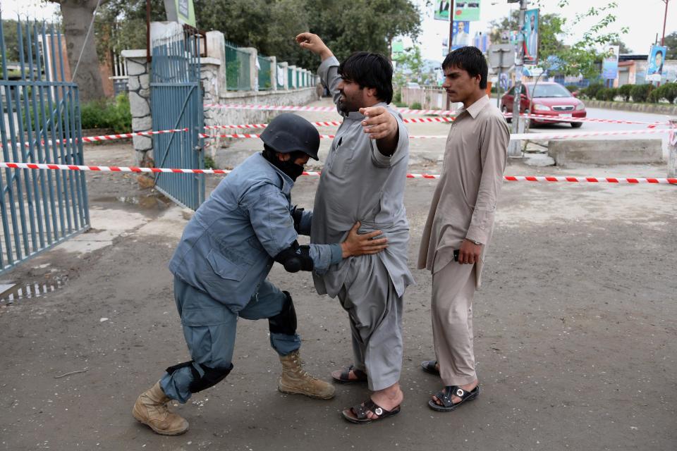 An Afghan policeman frisks a man at a polling station in Jalalabad, east of Kabul, Afghanistan, Saturday, April 5, 2014. Across Afghanistan, voters turned out in droves Saturday to cast ballots in a crucial presidential election. The vote will decide who will replace President Hamid Karzai, who is barred constitutionally from seeking a third term. (AP Photo/Rahmat Gul)