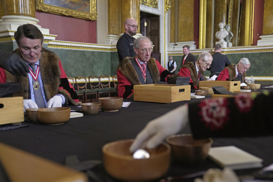 Coins are assessed during the "Trial of the Pyx,'' a ceremony that dates to the 12th Century in which coins are weighed in order to make certain they are up to standard, at the Goldsmiths' Hall in London, Tuesday, Feb. 7, 2023. A jury sat solemnly in a gilded hall in central London on Tuesday, presided over by a bewigged representative of the crown in flowing black robes, but there were no criminals in the dock. (AP Photo/Kin Cheung)