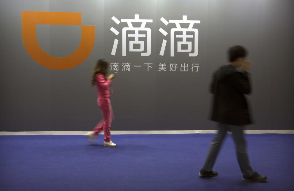 FILE - In this April 27, 2017, file photo, visitors walk past a sign for Chinese ride-hailing service Didi Chuxing at the Global Mobile Internet Conference (GMIC) in Beijing. China’s internet watchdog said Friday, July 2, 2021 that it has launched an investigation into ride-hailing company Didi Global Inc. to protect national security and public interest, days after the company went public in New York. (AP Photo/Mark Schiefelbein,File)