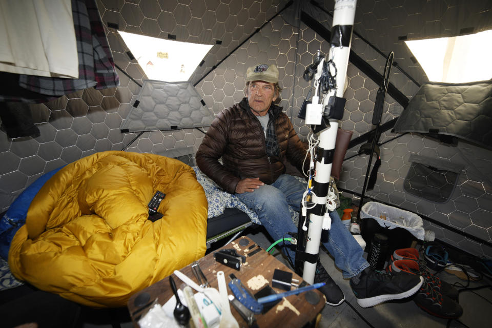 Gary Peters takes a break in his tent at the east safe outdoor space in the parking lot of the city of Denver Human Service building in Denver on Thursday, Feb. 17, 2022. The safe space is home to more than 150 people. (AP Photo/David Zalubowski)
