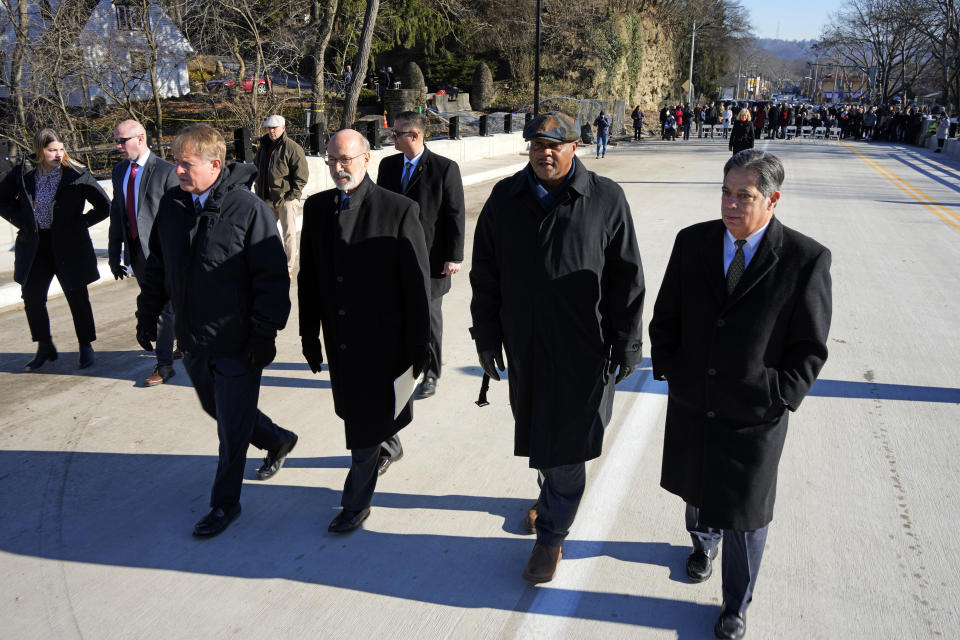 Allegheny County Executive Rich Fitzgerald, left, Pennsylvania Governor Tom Wolf, Pittsburgh Mayor Ed Gainey, and Pennsylvania State Senator Jay Costa walk across the rebuilt Fern Hollow Bridge before a dedication ceremony in Pittsburgh on Wednesday, Dec. 21, 2022. The original bridge collapsed during a snow storm on Jan. 28, 2022. The collapse of the Fern Hollow Bridge became a symbol of the country's troubled infrastructure. (AP Photo/Gene J. Puskar)