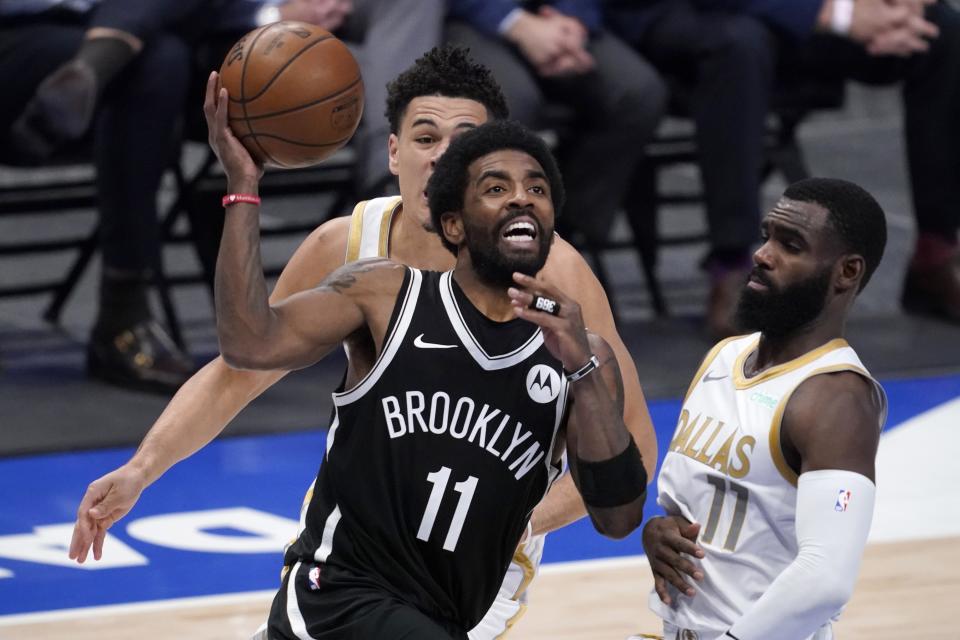 Brooklyn Nets guard Kyrie Irving (11) drives to the basket for a shot past Dallas Mavericks guard Josh Green, rear, and Tim Hardaway Jr., right, in the second half of an NBA basketball game in Dallas, Thursday, May 6, 2021. (AP Photo/Tony Gutierrez)