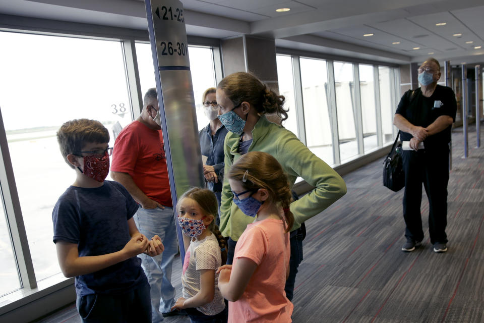 FILE - People wearing masks wait to board a Southwest Airlines flight at Kansas City International airport in Kansas City, Mo., in this May 24, 2020, file photo. Governments and businesses are scrambling to change course following new federal guidance calling for the return of mask wearing in virus hot spots amid a dramatic spike in COVID-19 cases and hospitalizations nationwide. Nevada and Kansas City were among the locations that moved swiftly to re-impose indoor mask mandates following Tuesday’s, July 27, 2021, announcement from the Centers for Disease Control and Prevention. (AP Photo/Charlie Riedel, File)