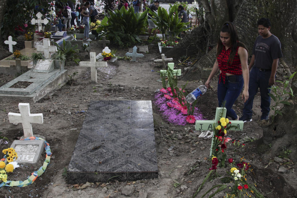 A couple walks next to one of the graves of gang members whose tombstone was destroyed on order of the government, during the Day of the Dead at the Nueva San Salvador Cemetery, in Santa Tecla, El Salvador, Wednesday, Nov. 2, 2022. Santa Tecla Mayor Henry Flores said the crews had destroyed nearly 80 tombstones in the municipal cemetery and erased gang-related graffiti. (AP Photo/Salvador Melendez)