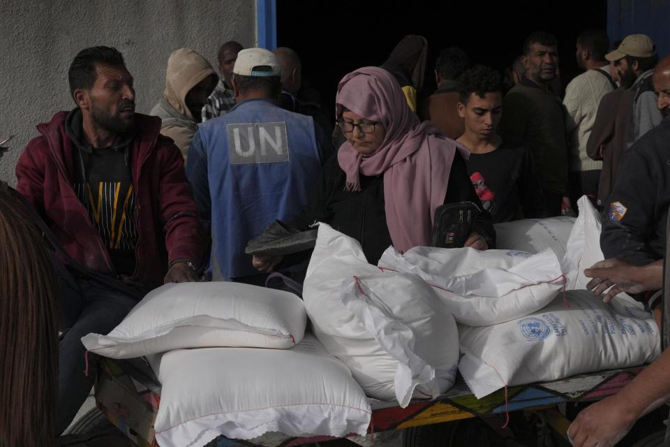 Palestinians take wheat from a U.N. distribution center in the Bureij refugee camp in the Gaza Strip on Sunday, Dec. 10, 2023. (AP Photo/Hatem Moussa)