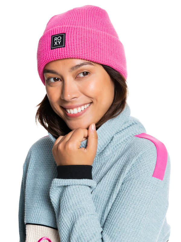 a model wears a pink Women's Harper Beanie with a blue turtleneck sweater with pink, navy and white details.