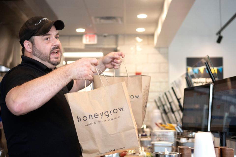 District manager Clinton Cox passes an order at Honeygrow's new location opening in Quakertown on Friday, June 3, 2022. This new location is the Philadelphia-based company's 27th since its first store in 2012.