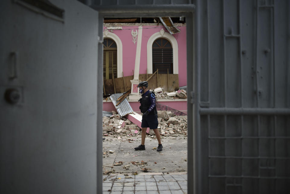 A police officer, wearing s protective face mask as a precaution against the spread of the new coronavirus, walks past debris caused by a 5.4-magnitude earthquake, in Ponce, Puerto Rico, Saturday, May 2, 2020. The quake hit near southern Puerto Rico, jolting many from their beds on an island where some people still remain in shelters from previous quakes earlier this year. (AP Photo/Carlos Giusti)