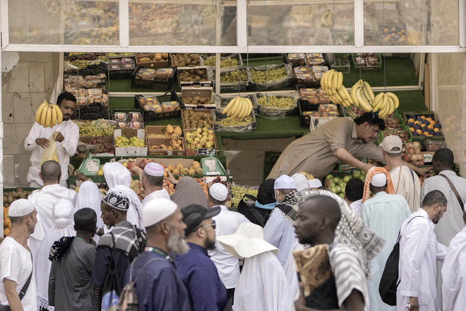 Muslim pilgrims buy fruits outside the Grand Mosque, during the annual hajj pilgrimage, in Mecca, Saudi Arabia, Friday, June 23, 2023. Muslim pilgrims are converging on Saudi Arabia's holy city of Mecca for the largest hajj since the coronavirus pandemic severely curtailed access to one of Islam's five pillars. (AP Photo/Amr Nabil)