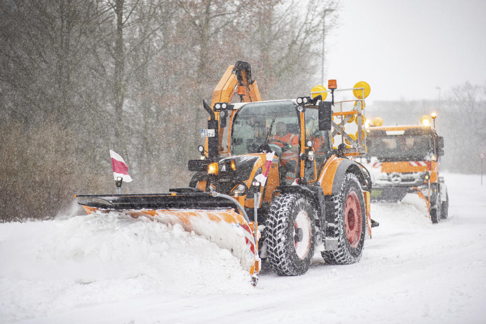 Clearing vehicles push piles of snow off a road in Bielefeld, Germany, Sunday, Feb. 7, 2021. (Marcel Kusch/dpa via AP)