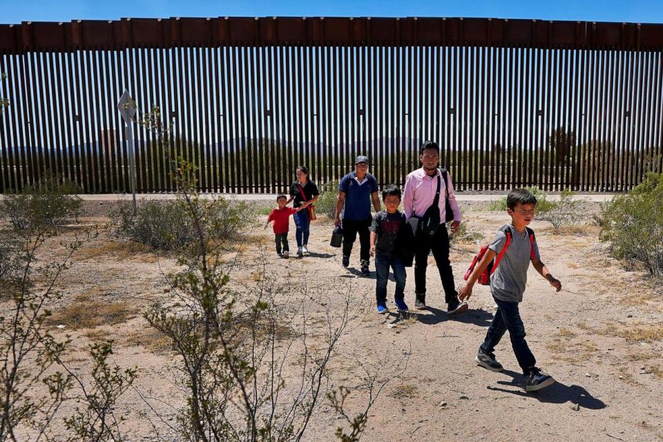 PHOTO: In this Aug. 29, 2023, file photo, a family of five claiming to be from Guatemala and a man stating he was from Peru, walk after crossing the border wall, in Organ Pipe Cactus National Monument near Lukeville, Ariz. (Matt York/AP, FILE)