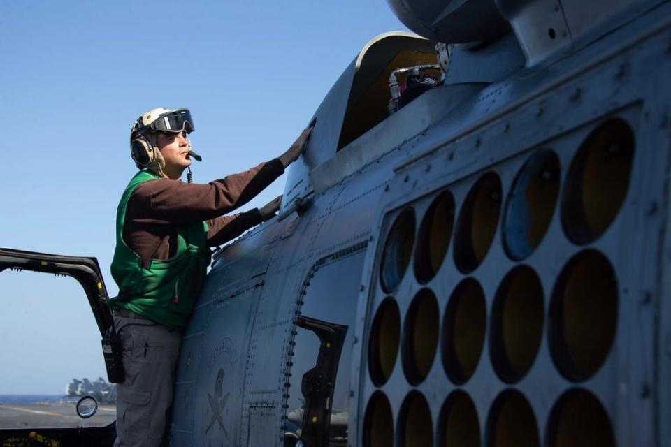 A photo of a man conducting maintenance on a helicopter.