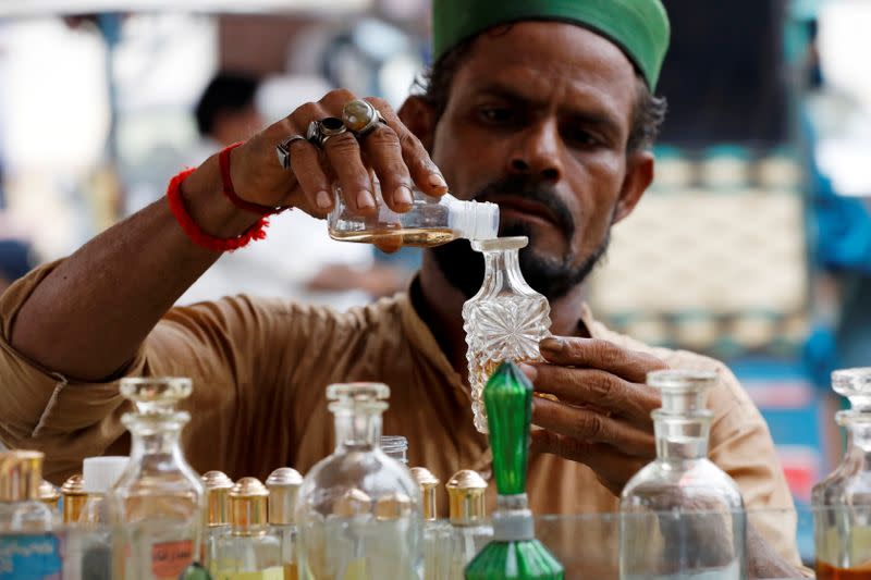 A man pours bottle with oil perfume along a wholesale market in Karachi