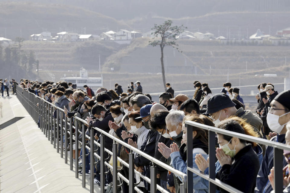 Un grupo de personas guarda un minuto de silencio a las 14:46 horas para conmemorar el momento en el que un potente sismo remeció Rikuzentakata, en la prefectura de Iwate, el 11 de marzo de 2023. (Kyodo News vía AP)