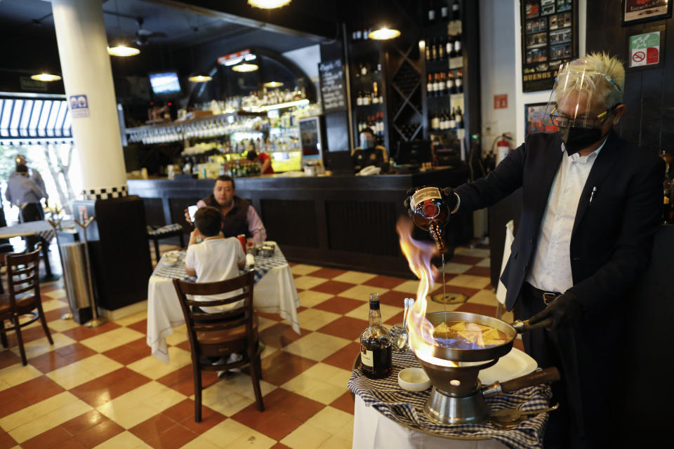 A waiter prepares an order of crepes Suzette inside Argentine grill Quebracho, in the Cuauhtemoc neighborhood of Mexico City, Monday, Jan. 11, 2021. More than three weeks into Mexico City's second pandemic shutdown some restaurateurs worried about their ability to survive ignored official warnings and opened limited seating Monday under the slogan, "Abrir o Morir," Spanish for "Open or Die." (AP Photo/Rebecca Blackwell)